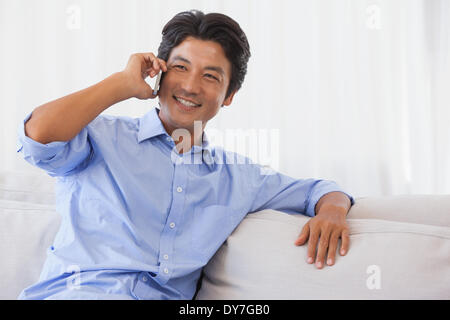 Glücklicher Mann sitzen auf der Couch am Telefon Stockfoto