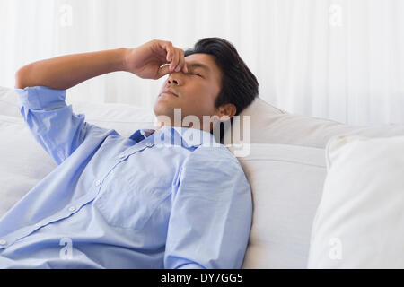 Mann sitzt auf der Couch mit Kopfschmerzen Stockfoto