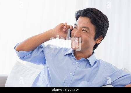 Glücklicher Mann entspannend auf Couch am Telefon sprechen Stockfoto