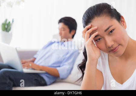 Verärgert Frau sitzen auf der Couch, während Freund Laptop verwendet Stockfoto