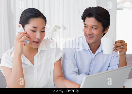 Paar mit Laptop mit Frau am Telefon Stockfoto