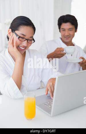 Paar im Bademantel, die er am Morgen zusammen mit laptop Stockfoto