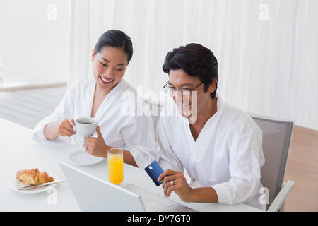 Paar in Bademäntel Online-shopping in den Morgen Stockfoto