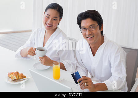 Paar in Bademäntel Online-shopping in den Morgen Stockfoto