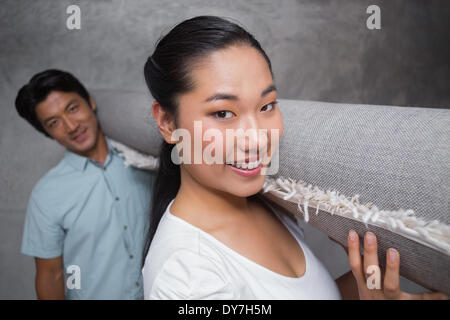 Glückliches Paar hält einen gerollten Teppich Stockfoto