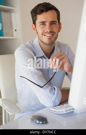 Lässige Geschäftsmann lächelnd in die Kamera an seinem Schreibtisch Stockfoto