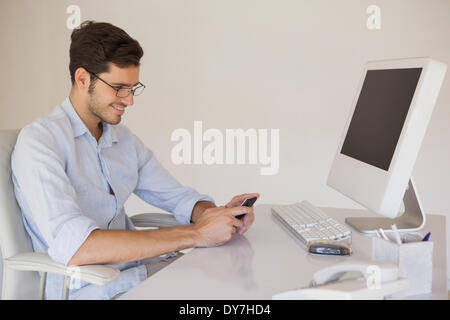 Lässige Geschäftsmann eine SMS an seinem Schreibtisch Stockfoto