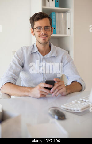 Lässige Geschäftsmann eine SMS an seinem Schreibtisch Stockfoto