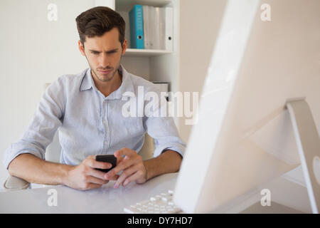 Lässige Geschäftsmann eine SMS an seinem Schreibtisch Stockfoto