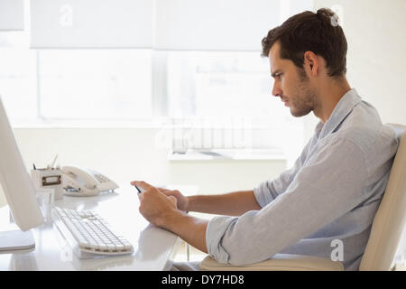 Lässige Geschäftsmann eine SMS an seinem Schreibtisch Stockfoto
