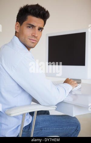 Lässige Geschäftsmann arbeitet an seinem Schreibtisch, Blick in die Kamera Stockfoto