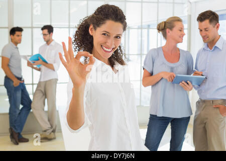 Lässige Geschäftsfrau verleihen Kamera ok Sign. Stockfoto