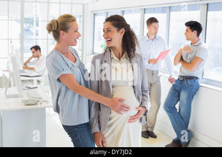 Lässige Geschäftsfrau berühren Bauch schwanger Kollegen Stockfoto