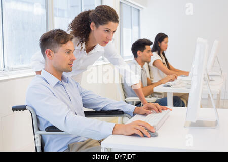 Lässige Geschäftsmann im Rollstuhl, die Arbeit an seinem Schreibtisch mit Kollegen Stockfoto