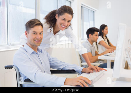 Lässige Geschäftsmann im Rollstuhl, die Arbeit an seinem Schreibtisch mit Kollegen Stockfoto