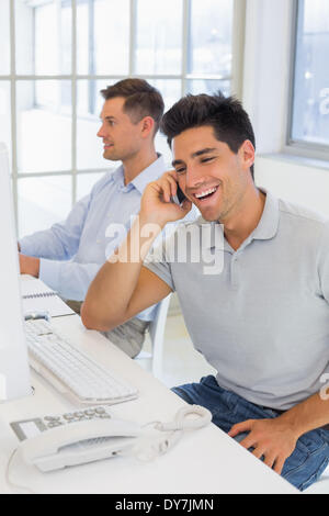 Lässige Geschäftsmann lachend am Telefon am Schreibtisch Stockfoto