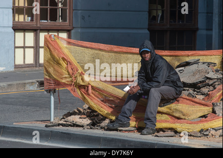 Obdachloser sitzt auf einige Trümmer Baustelle, Cape Town, Südafrika Stockfoto