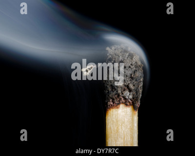 Ein Brandopfer nach ausgeblasen werden kann, zeigt der Rauch, die von diesem anpassen, auf einem schwarzen Hintergrund. Verbrannt übereinstimmen. Stockfoto