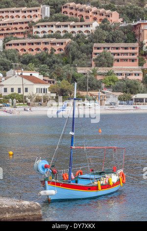 Kalami Bucht, Korfu, mit neuen Ferienhäuser auf der Klippe und einem traditionellen Fischerboot vor Anker im Vordergrund (Name entfernt). Stockfoto