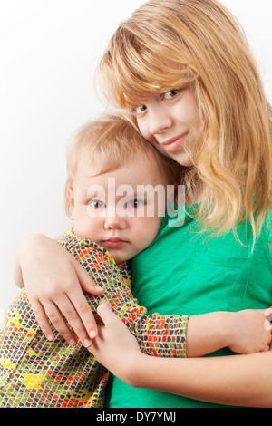 Kleine blonde kaukasische Schwestern umarmen. Closeup Portrait auf weißem Hintergrund Stockfoto