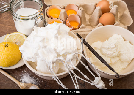 Schüssel mit Eischnee und andere Backzutaten Meringues auf Holztisch Stockfoto