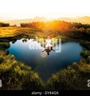 Österreich, Salzburger Land, Altenmarkt-Zauchensee, Meditierenden Frau am Teich Stockfoto