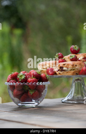 Erdbeeren in ein Glas Schüssel, Scones mit Sahne und Marmelade auf eine Kuchenplatte Stockfoto