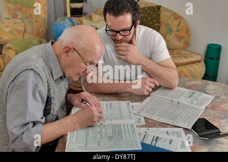 Enkel hilft seinem Großvater durch eine Steuererklärung Stockfoto