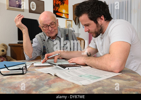 Enkel hilft seinem Großvater durch eine Steuererklärung Stockfoto
