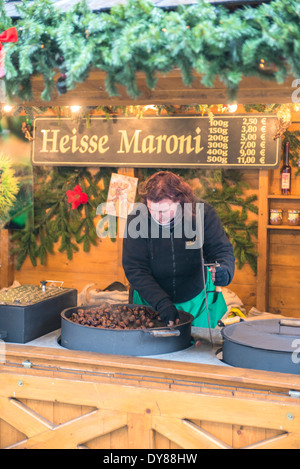 Frau rösten Kastanien (Marone) am Weihnachtsmarkt, Bamberg, Deutschland Stockfoto