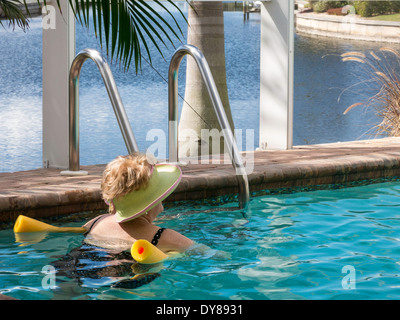 Reife Frau faulenzen Pool mit Pool-Nudel, Florida, USA Stockfoto