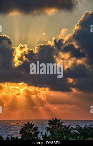 Sonnenuntergang mit Sonnenstrahlen durch die Wolken über Meer Stockfoto