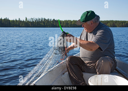 Älterer Mann überprüfen Fischernetze am See, Finnland Stockfoto