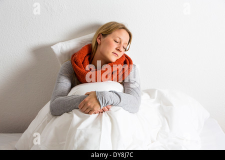 Junge Frau fühlt sich unwohl, hat eine Kälte, Grippe, im Bett liegend Stockfoto