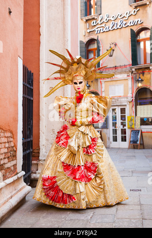 Maskierte Frau im goldenen Ball Kleid Kostüm posiert während des Karnevals in Venedig Stockfoto