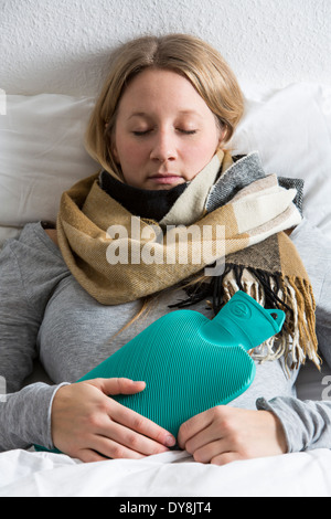 Junge Frau in Schmerzen, lindert die Schmerzen im Zusammenhang mit einer Wärmflasche Stockfoto