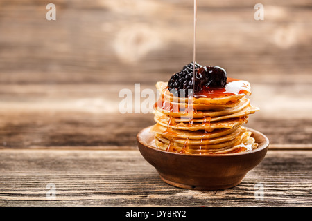 Honig in Strömen über einen Stapel von Mini-Pfannkuchen Stockfoto