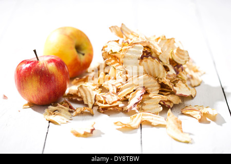 Zwei Äpfel und ein Haufen von getrocknete Apfelringe auf weißer Holztisch Stockfoto