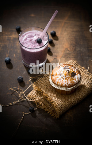 Glas Heidelbeeren Milchshake, Blueberry Muffin und Blaubeeren auf Holztisch, erhöht, Ansicht Stockfoto