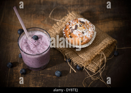 Glas Heidelbeeren Milchshake, Blueberry Muffin und Blaubeeren auf Holztisch, erhöht, Ansicht Stockfoto