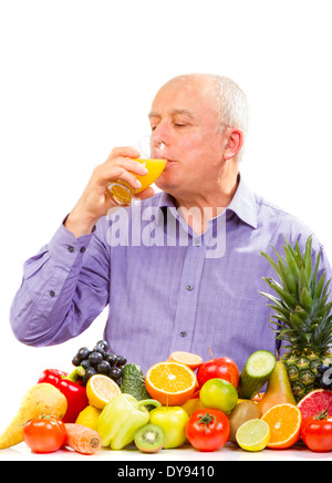 Reifer Mann Saft zu trinken und stand neben Obst und Gemüse isoliert auf weiss Stockfoto