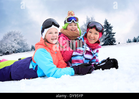 Deutschland, Masserberg, Mutter und Töchter liegen im Schnee, glücklich lächelnd Stockfoto