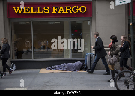 Die Menschen gehen übrigens kaum zu bemerken, ein Obdachloser schläft vor einer Bank in Midtown Manhattan. Stockfoto