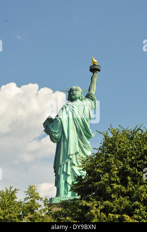 Rückansicht der Freiheitsstatue hinter Baum tops blauen Himmel mit Wolken nach links Stockfoto