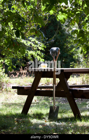 Einen Garten Spaten ruhen gegen ein Holztisch mit Kräutertee Stockfoto