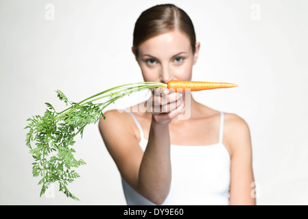 Junge Frau hält rohe Karotte Stockfoto