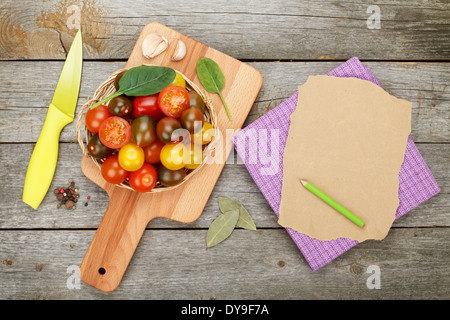 Cherry-Tomaten auf Schneidebrett über Holztisch Hintergrund mit Papier für Textfreiraum Stockfoto