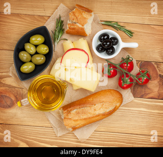 Frischkäse, Brot, Oliven und Tomaten auf Holztisch Hintergrund. Über Ansicht Stockfoto