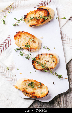 Gebratenes Brot Croutons mit Thymian und Spinat lässt auf weiße Schneidebrett. Ansicht von oben Stockfoto