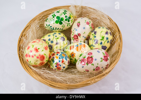 Gruppe von bunten Ostereiern dekoriert mit Blumen von Decoupage-Technik, in einem Korb auf hellem Hintergrund Stockfoto